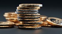 Stack of golden coins with detailed ridged edges on dark background representing wealth, savings, investment and financial growth concepts for business use.