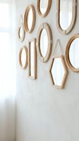 Collection of wooden geometric mirrors in various shapes hanging on white wall creating modern minimalist home decor gallery wall arrangement.