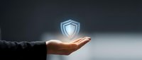 Businessman hand holding glowing shield icon symbolizing data protection, cybersecurity, and digital safety for business and technology concepts.