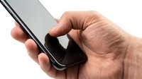 Caucasian male hand holding a modern smartphone with dark screen, close-up view on white background, isolated for design use.