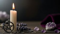 Mystical altar setup with burning candle, pentagram pendant, amethyst crystals and lavender sprigs for spiritual rituals and meditation practices.