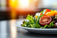 Fresh garden salad with roasted cherry tomatoes, crisp lettuce leaves, and colorful bell peppers served on white plate against blurred warm background.