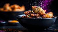 Crispy glazed chicken pieces in black bowl with purple spice powder falling, dramatic dark food photography with selective focus and copy space.