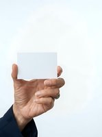Male hand holding blank white card against neutral background, suitable for business presentations, advertising campaigns, promotional materials, and corporate communications.