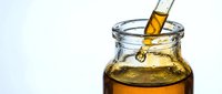 Pouring golden honey into glass jar against white background, isolated ingredient for cooking, baking, and food preparation projects.