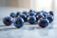 Fresh ripe blueberries scattered on marble surface with water drops and morning light creating soft shadows, macro food photography for healthy eating concept.