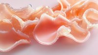 Fresh raw salmon slices arranged in wavy pattern showing delicate texture and natural coral-pink color against light background, macro food photography.