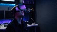Young Caucasian man wearing VR headset in futuristic gaming setup with purple neon lighting exploring virtual reality technology in modern dark room.
