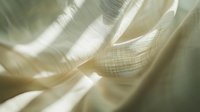 Ethereal cream colored fabric with delicate folds creates soft shadows and light patterns, showcasing gentle textile movement and flowing curves in macro photography.