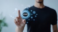 Young businessman touching virtual start button with digital interface elements and glowing network connections for technology and innovation concepts.