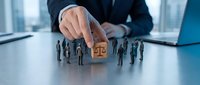 Professional businessman in suit selecting candidate from group of miniature figures with justice scales symbol on modern office desk for HR recruitment concept.