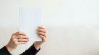 Adult hands holding blank white card against neutral background for messaging or branding purposes.