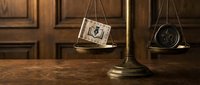 Vintage brass scales of justice with money and gavel on wooden desk representing legal fees, attorney costs, and judicial system economics in law office.