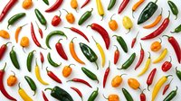 Colorful assorted hot chili peppers scattered on white background. Fresh spicy vegetables including jalapeno, habanero and cayenne varieties for cooking.