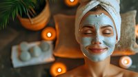 Young woman with clay facial mask relaxing at spa with candles and plants in background. Wellness and skincare concept.