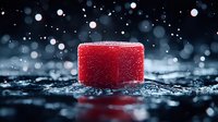 Red ice cube on dark wet surface with bokeh lights and water drops in background creates magical winter atmosphere for festive seasonal designs.