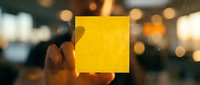 Young adult male with medium skin tone holding glowing yellow square against blurred urban evening backdrop with bokeh lights, suitable for business, technology, innovation, and creative concept designs.