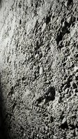 Rough textured concrete wall surface with porous holes and weathered finish for industrial construction and architectural backgrounds.