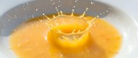 Yellow liquid splash with crown formation on white background, suitable for beverage, juice, and product advertising designs.