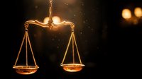 Golden scales of justice glowing in warm light against dark background symbolizing law, legal system, fairness and judicial balance in courtroom setting.