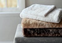 Folded soft towels in white, beige and brown colors stacked on gray surface, creating minimalist composition for spa, bathroom and wellness design.