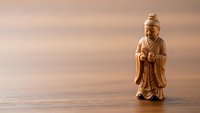 Wooden Buddha statue figurine on natural wood surface with soft lighting creating peaceful meditation and mindfulness atmosphere for spiritual decor.