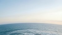 Serene ocean horizon with calm blue waters meeting pastel sky at sunset, peaceful seascape with soft lighting for relaxation and travel content.