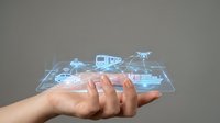 Male hand holding glowing holographic display with connected technology icons including drone, vehicle, and wireless network symbols for digital innovation and smart device concepts.