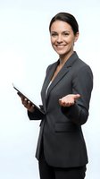 Professional businesswoman in gray suit holding tablet with welcoming gesture on white background for corporate presentations and marketing materials.