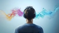 Young Asian man wearing headphones with colorful smoke flowing from both sides against light background, representing music therapy and audio experience.