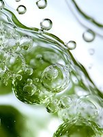 Macro photography of water bubbles and droplets floating in green liquid creating abstract patterns and reflections, captured with high-speed technique.