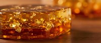 Amber resin with golden inclusions and natural textures creating warm honey-colored translucent material for jewelry making and decorative crafts.