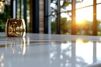 Golden glass candle holder on white marble table with warm sunlight streaming through windows creating elegant home interior atmosphere.