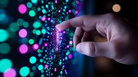 Magical finger touch creating sparkly burst of pink and turquoise bokeh lights against dark background, digital transformation concept for technology innovation.