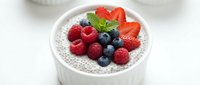 Chia seed pudding topped with fresh mixed berries including strawberries, raspberries and blueberries in white bowl for healthy breakfast or dessert.