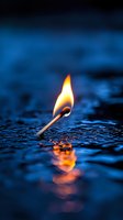 Burning match with bright flame reflecting on wet dark blue surface creates dramatic contrast between fire and water, suitable for conceptual designs and metaphors.