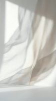 Soft white fabric draping elegantly with natural window light creating gentle shadows and highlights for minimalist interior design concepts.