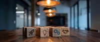 Modern office workspace with wooden blocks displaying business strategy icons on conference table under warm pendant lighting for corporate planning presentations.