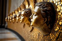 Golden decorative wall sculptures featuring classical female profiles against mosaic background create dramatic architectural detail in luxury interior design.