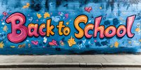 Colorful back to school graffiti text on blue wall with flying letters, numbers, and hearts. Street art style education concept with concrete sidewalk.