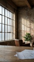 Industrial loft interior with exposed brick walls, large factory windows, leather armchair and wooden ceiling beams creating warm atmospheric workspace.