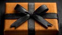Elegant orange gift box with black ribbon bow on dark surface for special occasions and celebrations.