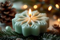 Decorative snowflake-shaped candle burning with warm flame surrounded by pine cones and evergreen branches creating cozy winter holiday atmosphere.
