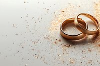 Gold wedding rings on light background with golden glitter sparkles, romantic marriage symbol for wedding invitations and anniversary cards.