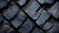 Rough textured black coal chunks arranged in diagonal pattern with orange rusty spots and deep shadows creating industrial mining background.