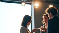 Young diverse professionals collaborating in modern office space with warm lighting and industrial design elements during business meeting.