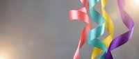 Colorful flowing ribbons in pink, blue, yellow and purple creating dynamic movement against soft gradient background for celebration and festive designs.