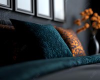 Luxurious teal blue damask pillows on bed with soft natural lighting through windows, creating cozy bedroom atmosphere with orange floral accents.