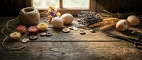 Rustic wooden table with craft supplies including yarn, buttons, dried flowers, eggs and wicker basket near sunny window for creative hobby projects.