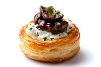 Flaky puff pastry vol-au-vent filled with creamy mushroom sauce and sauteed wild mushrooms, garnished with fresh herbs on white background.